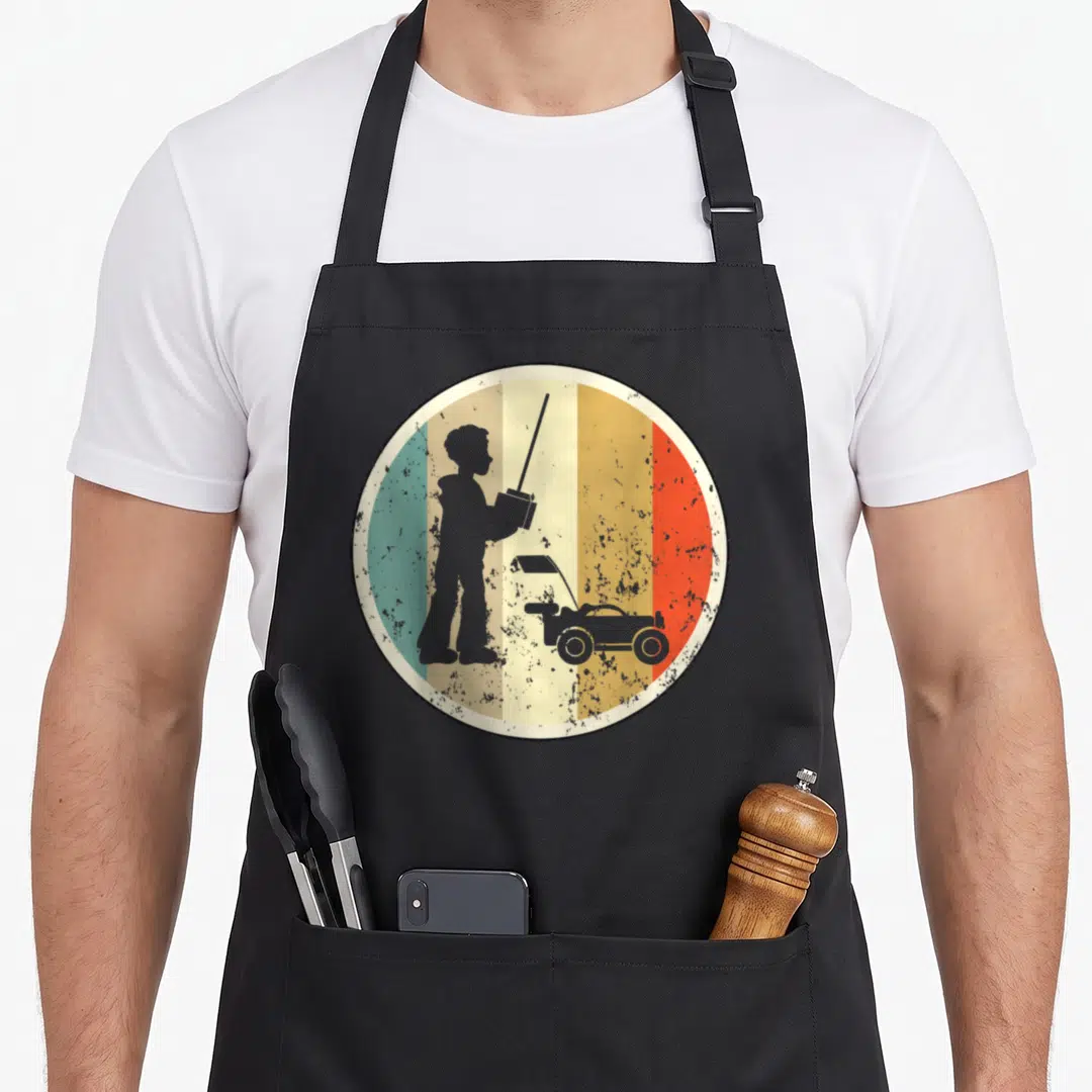 Model car apron - Grey silhouette of boy holding remote control car over red orange yellow green stripes — shown on a black cotton canvas apron against a white background
