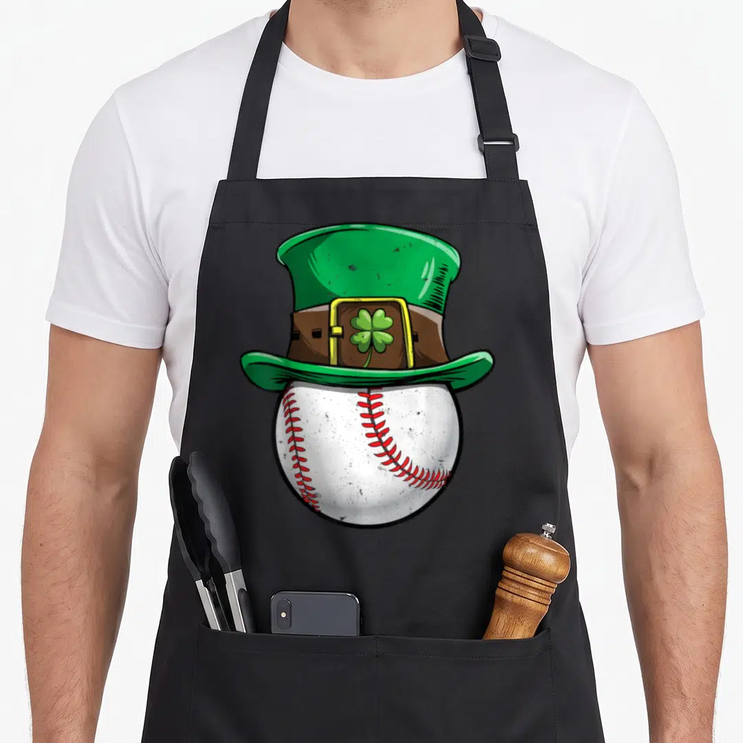 Ball st patrick day aprons - Green leprechaun hat with gold buckle and shamrock sitting on top of a white baseball — shown on a black cotton canvas apron against a white background