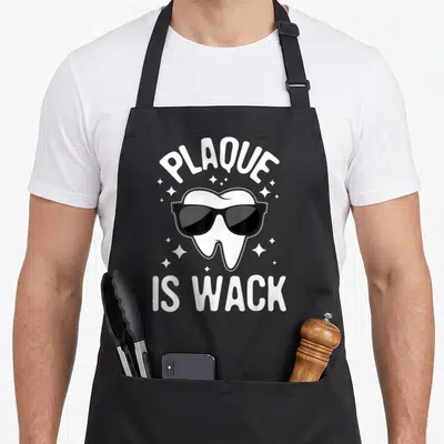 Wack dentist apron - Cartoon tooth wearing black sunglasses with plaque is wack text and scattered stars — shown on a black cotton canvas apron against a white background