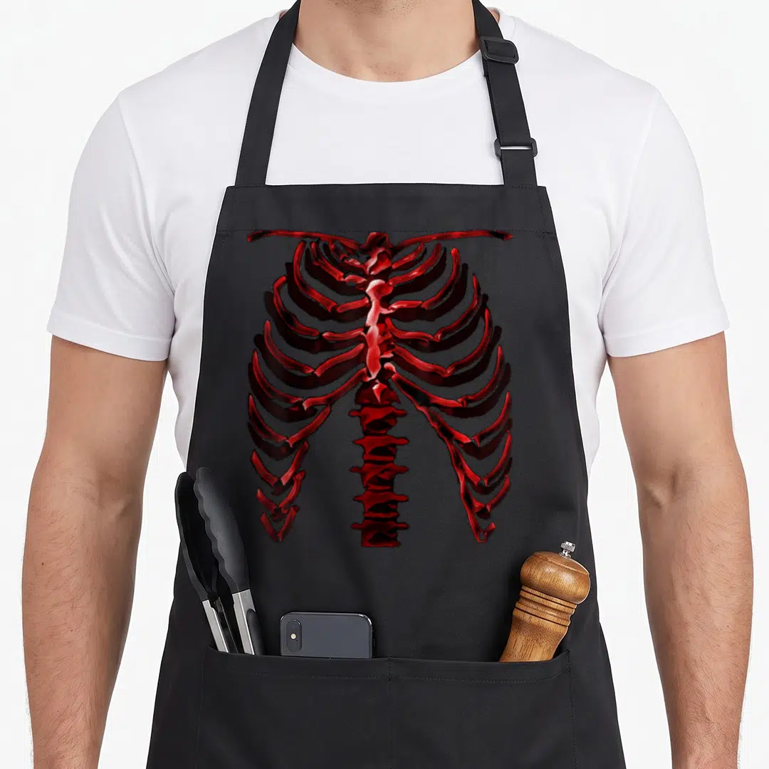 Ver halloween apron - Realistic red human ribcage and spine illustration on dark background — shown on a black cotton canvas apron against a white background