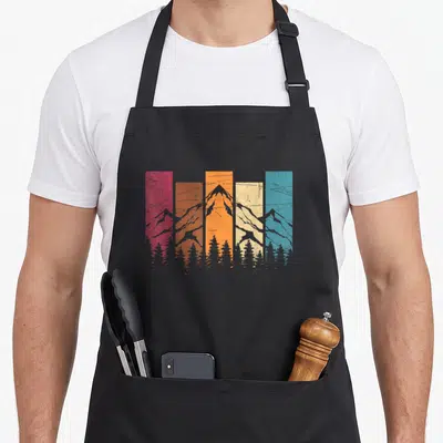 Hiker tree apron - Retro grey mountain and tree silhouettes over five red orange yellow cream and blue vertical stripes — shown on a black cotton canvas apron against a white background