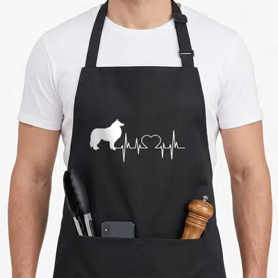 Scottish collie dog apron - White silhouette of a collie connected to a heartbeat line with a heart shape — shown on a black cotton canvas apron against a white background