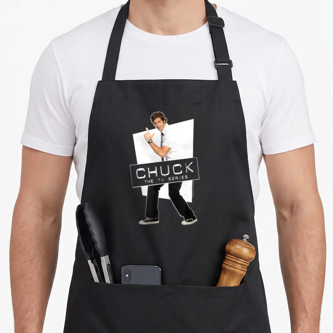 Chuck tech nerd apron - Man standing before white tilted rectangle with CHUCK THE TV SERIES banner — shown on a black cotton canvas apron against a white background
