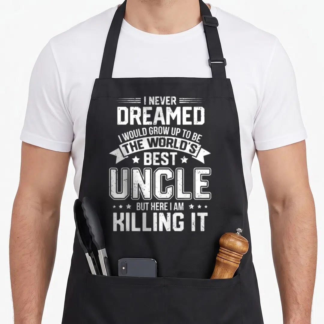 Funny uncle apron - White stacked text reading I Never Dreamed I Would Grow Up To Be The World's Best Uncle But Here I — shown on a black cotton canvas apron against a white background