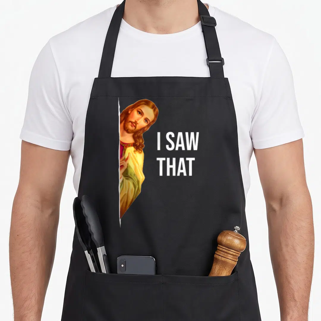 Jesus meme apron - Realistic Jesus peeking from behind white edge with I SAW THAT text in white — shown on a black cotton canvas apron against a white background