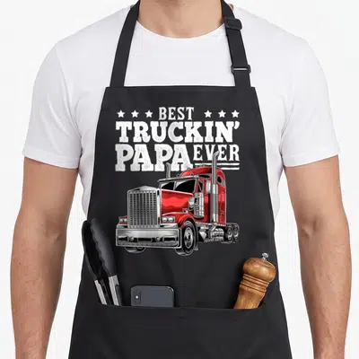 Rig father day apron - Red semi-truck illustration below stacked Best Truckin Papa Ever text surrounded by six white — shown on a black cotton canvas apron against a white background