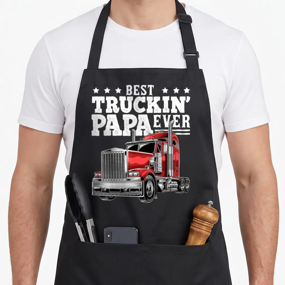 Rig father day apron - Red semi-truck illustration below stacked Best Truckin Papa Ever text surrounded by six white — shown on a black cotton canvas apron against a white background
