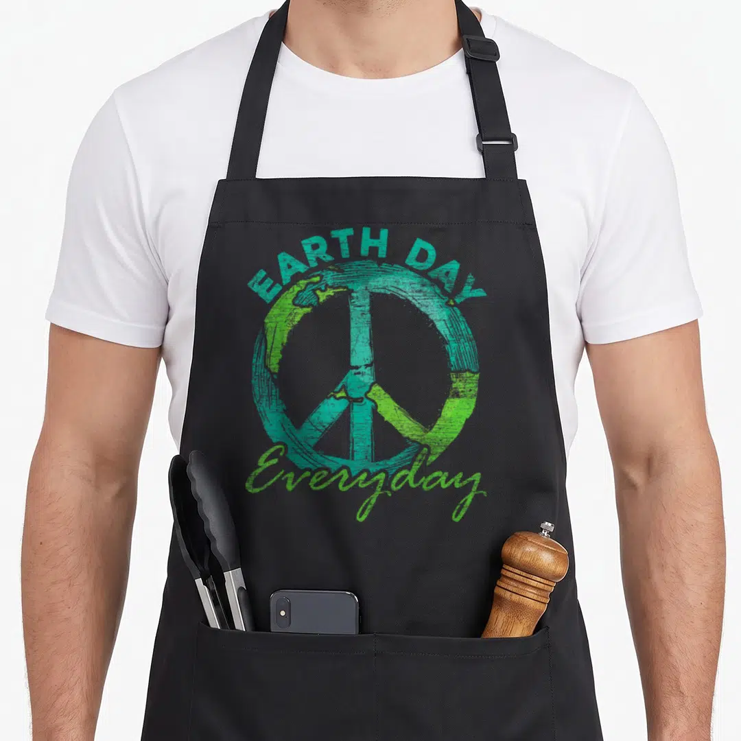 Funny earth everyday apron - Distressed teal and green peace sign with arched EARTH DAY text and script Everyday label — shown on a black cotton canvas apron against a white background