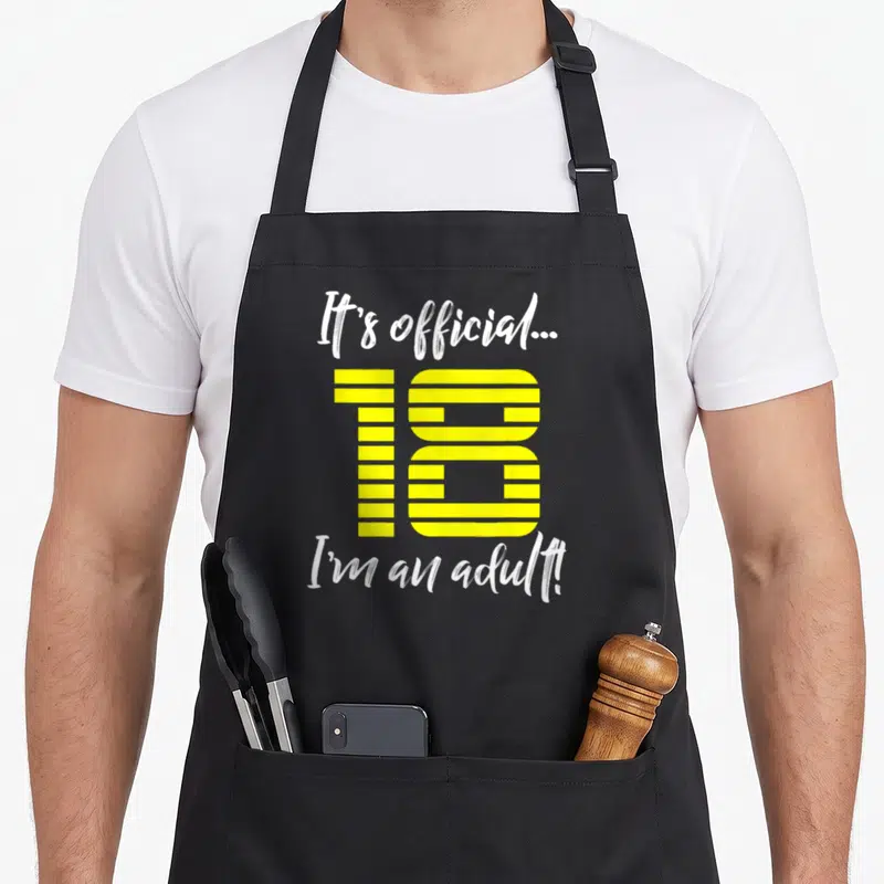 18th born day apron - White script text above yellow striped number 18 and bottom phrase on gray background — shown on a black cotton canvas apron against a white background