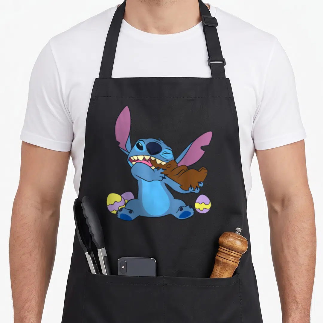 Stitch easter egg apron - Blue cartoon character biting brown bunny with yellow and purple eggs — shown on a black cotton canvas apron against a white background