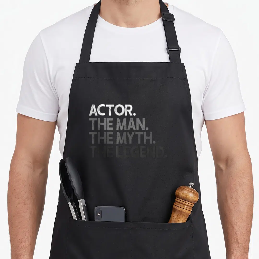 Myth actor apron - Stacked white to grey distressed text reading ACTOR THE MAN THE MYTH THE LEGEND — shown on a black cotton canvas apron against a white background
