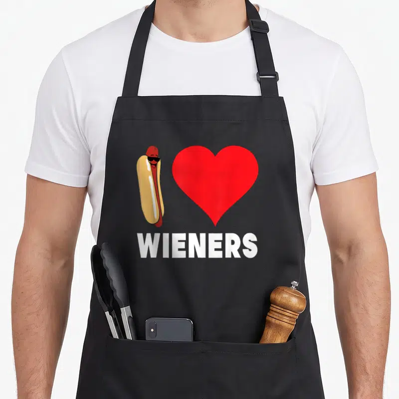 Lgbt wiener apron - Cartoon hot dog in sunglasses next to red heart with white text — shown on a black cotton canvas apron against a white background