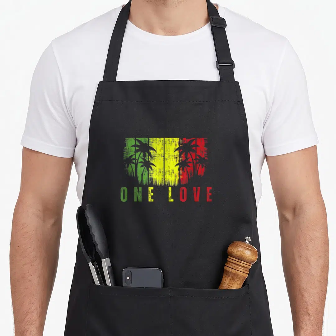 Reggae tree apron - Distressed green yellow red rectangle with black palm trees and ONE LOVE text below — shown on a black cotton canvas apron against a white background