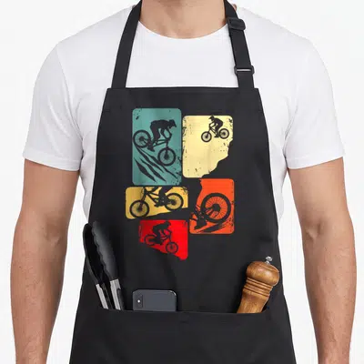 Mtb downhill bike apron - Four teal, yellow, orange, red, grey rectangles with grey mountain biker silhouettes — shown on a black cotton canvas apron against a white background