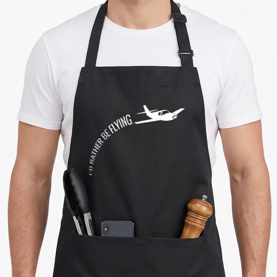 Rather airplane apron - White airplane silhouette with curved text I'D RATHER BE FLYING underneath — shown on a black cotton canvas apron against a white background