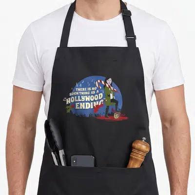 Anna apocalypse apron - Woman standing on severed head with candy cane and text THERE IS NO SUCH THING AS A HOLLYWOOD — shown on a black cotton canvas apron against a white background