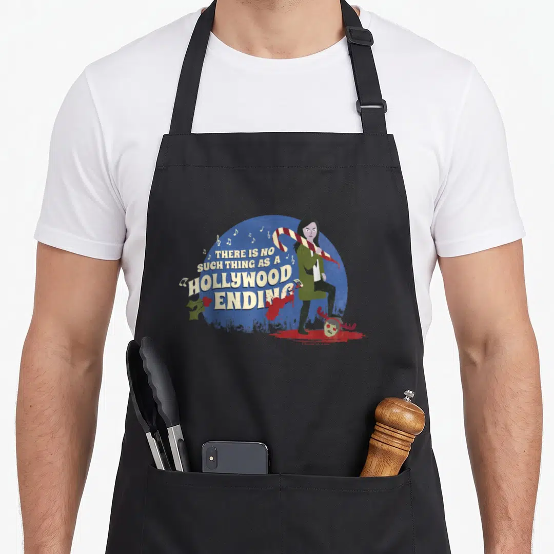 Anna apocalypse apron - Woman standing on severed head with candy cane and text THERE IS NO SUCH THING AS A HOLLYWOOD — shown on a black cotton canvas apron against a white background