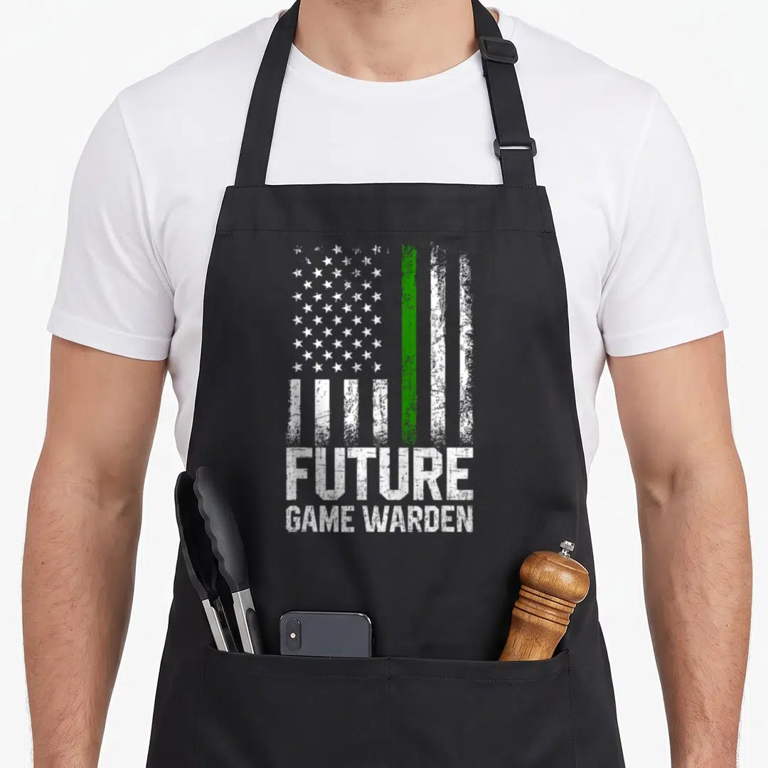 Future game aprons - Distressed white and green flag above FUTURE GAME WARDEN text on black fabric — shown on a black cotton canvas apron against a white background