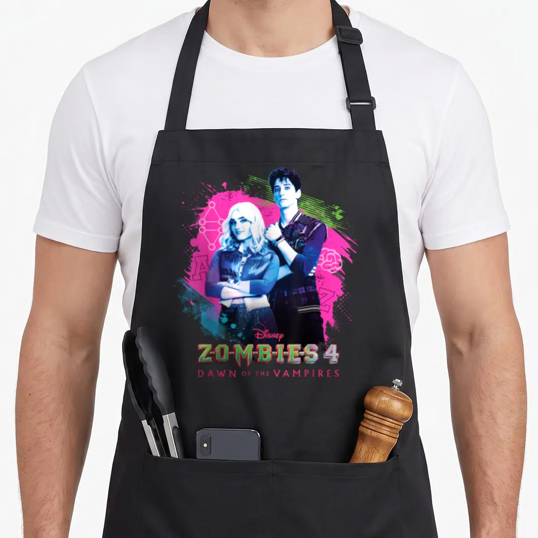 Dawn zombie apron - Two people standing centrally against pink blue and green paint splashes with stacked movie text — shown on a black cotton canvas apron against a white background