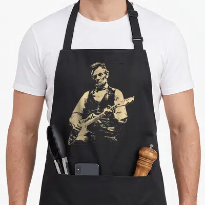 Abraham electric guitar apron - Distressed tan illustration of Abraham Lincoln playing an electric guitar in a vintage — shown on a black cotton canvas apron against a white background