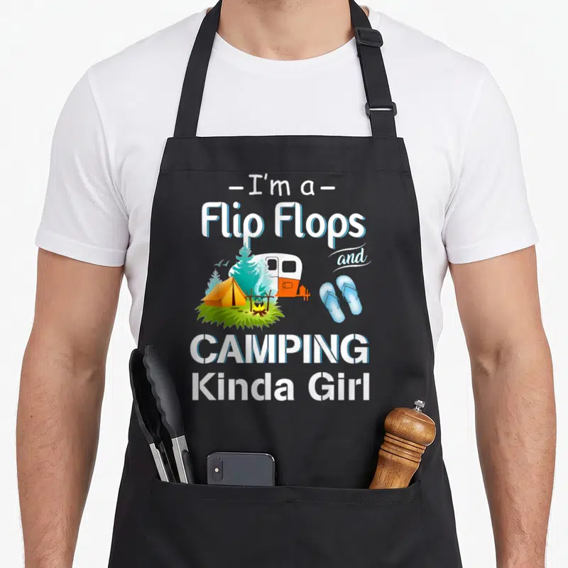 Retro camping apron - I'm a Flip Flops and CAMPING Kinda Girl text with camper tent and flip flops illustration — shown on a black cotton canvas apron against a white background