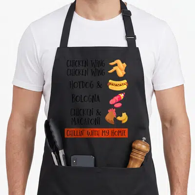 Bologna hot dog apron - Stacked food text listing chicken wing hotdog bologna and macaroni next to cartoon illustrations — shown on a black cotton canvas apron against a white background