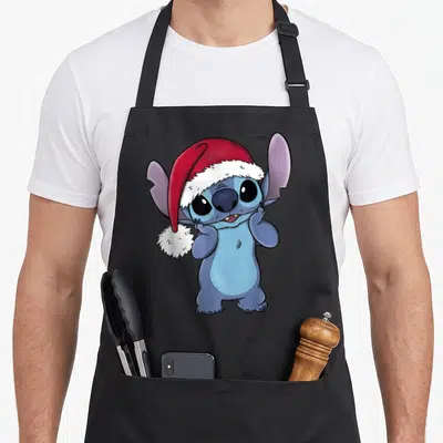 Christmas santa aprons - Blue cartoon character wearing a red and white Santa hat with large eyes — shown on a black cotton canvas apron against a white background