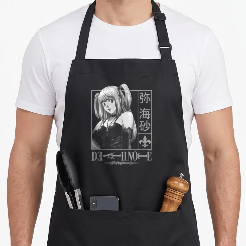 Misa anime apron - Woman in rectangular frame with kanji, fleur-de-lis, and DEATH NOTE text in white and grey — shown on a black cotton canvas apron against a white background