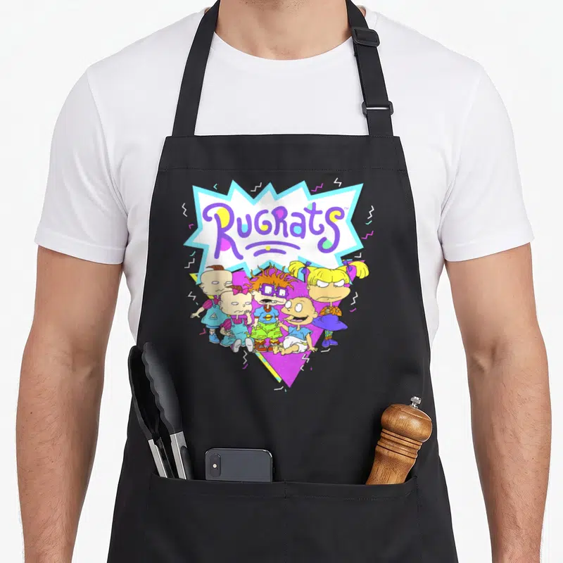 Geometric novelty apron - Rugrats text in burst above five cartoon babies in purple blue yellow pink — shown on a black cotton canvas apron against a white background