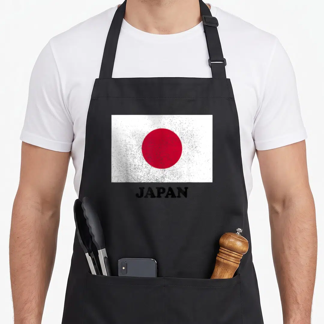 Flag pride japan apron - Distressed red circle flag on white background with black JAPAN text below — shown on a black cotton canvas apron against a white background