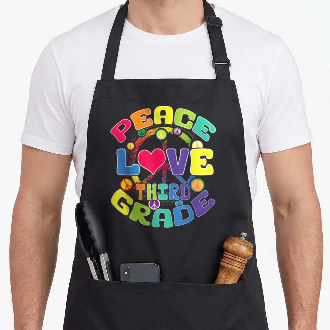 Peace classroom aprons - Stacked colorful text PEACE LOVE THIRD GRADE with pink heart and peace signs — shown on a black cotton canvas apron against a white background