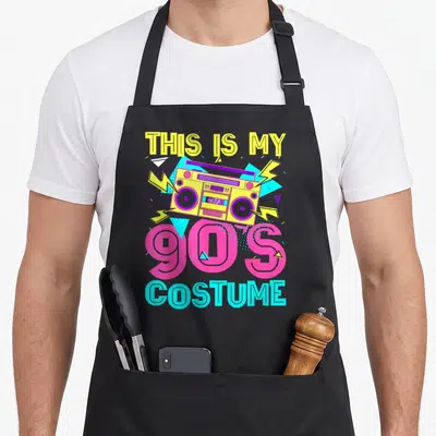 90s theme aprons - Yellow boombox with lightning bolts and text This Is My 90s Costume — shown on a black cotton canvas apron against a white background