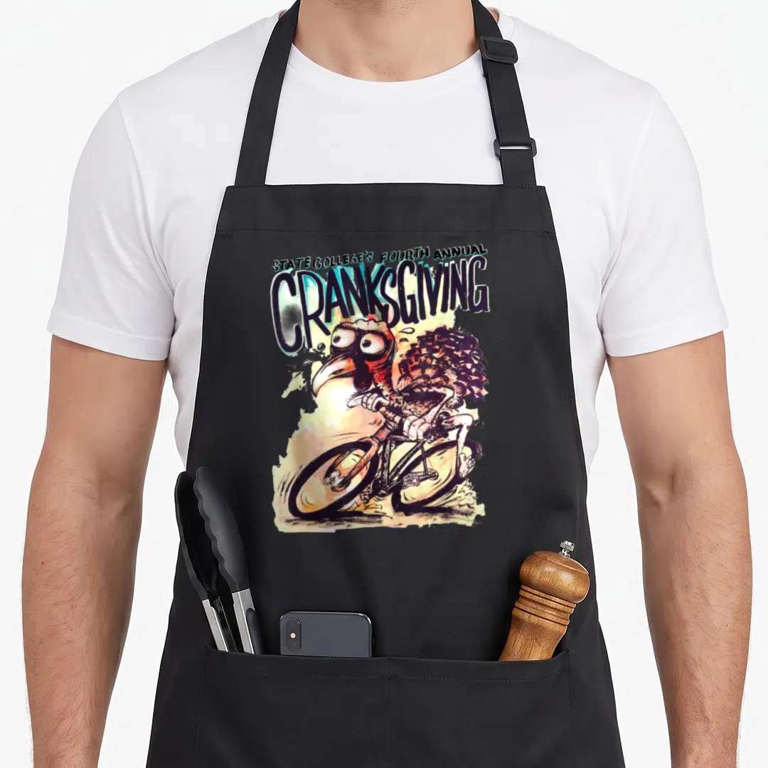 4th state college apron - Stacked text above a cartoon turkey riding a bicycle with wide eyes and sweat drops — shown on a black cotton canvas apron against a white background