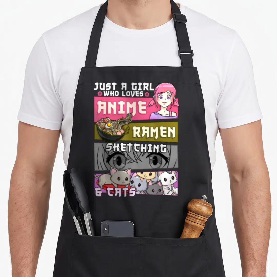 Sketching cat apron - Anime girl, ramen bowl, large eyes, and group of cats in stacked colored panels — shown on a black cotton canvas apron against a white background