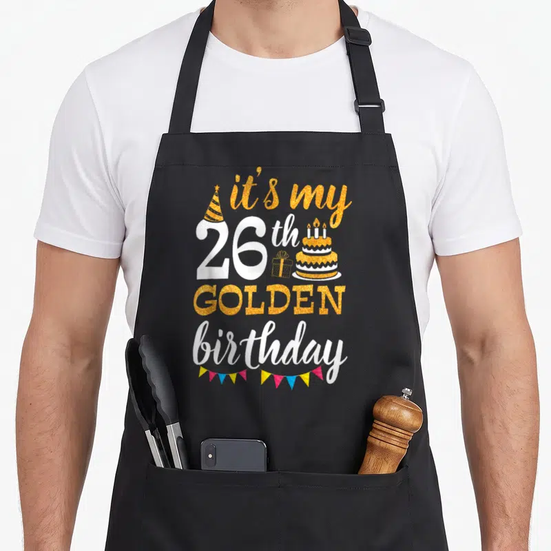 26th golden apron - Gold and white text it's my 26th GOLDEN birthday with cake gift and bunting flags — shown on a black cotton canvas apron against a white background