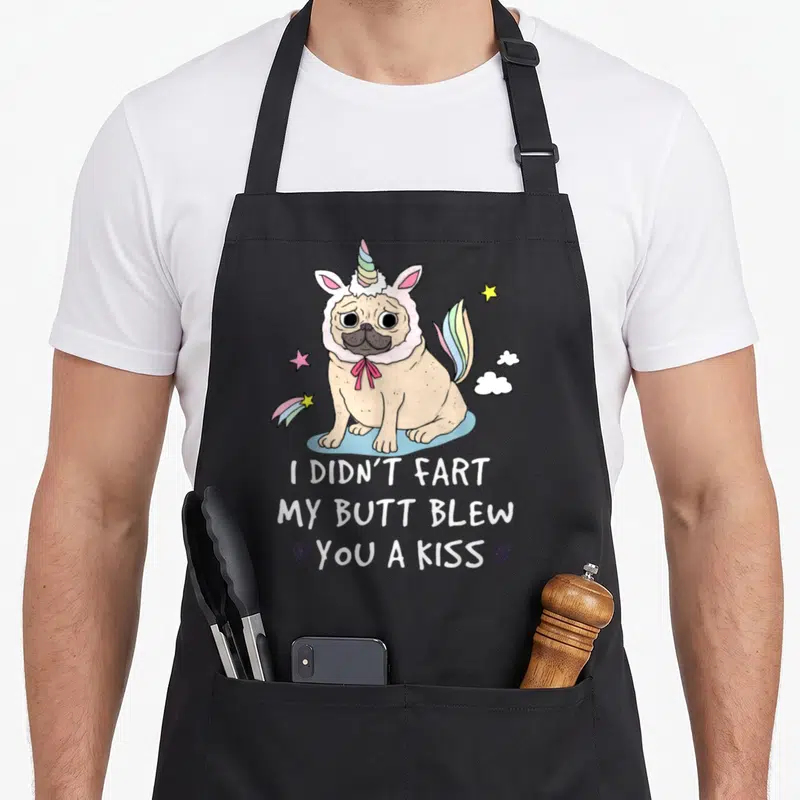 Pug grandma apron - Tan pug in unicorn costume with rainbow tail and text I Didn't Fart My Butt Blew You A Kiss — shown on a black cotton canvas apron against a white background