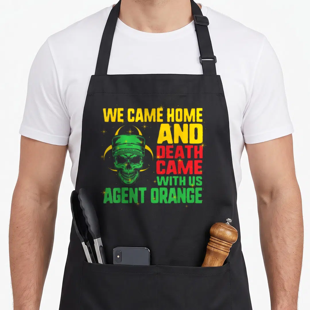 Agent vietnam apron - Green skull in cap overlapping yellow radiation symbol with stacked text We Came Home and Death — shown on a black cotton canvas apron against a white background