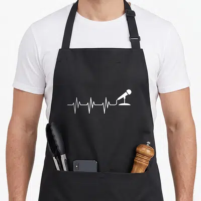 Microphone singing apron - White EKG heartbeat line connects to a microphone on a stand in minimalist style — shown on a black cotton canvas apron against a white background