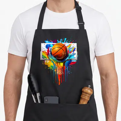 Colorful tie dye apron - Orange basketball and net dissolving into multicolored paint drips on a white backboard — shown on a black cotton canvas apron against a white background