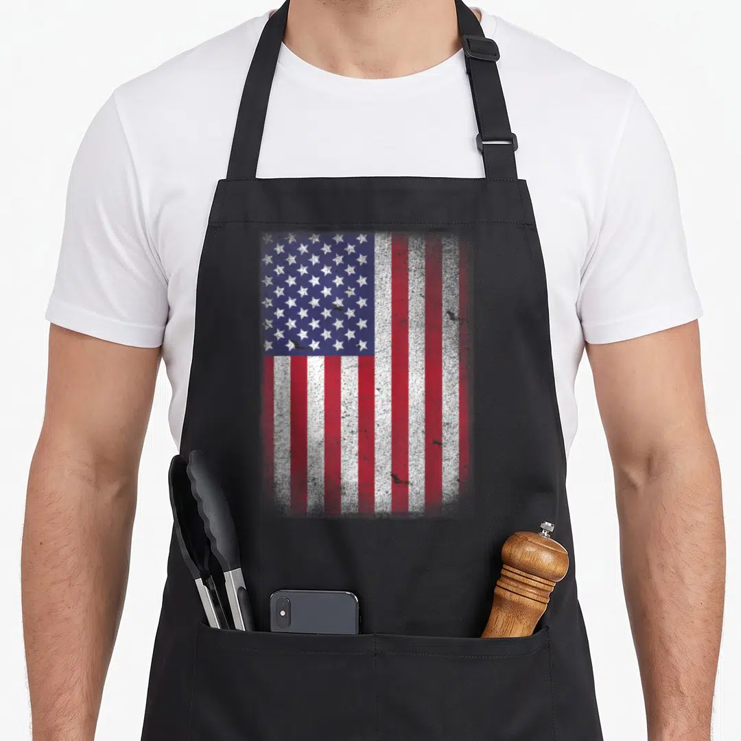 Blue 4th of july apron - Distressed American flag print in red white and blue on black fabric — shown on a black cotton canvas apron against a white background