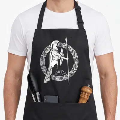 History greek aprons - White line art of helmeted warrior Ares with shield spear and Greek key border — shown on a black cotton canvas apron against a white background