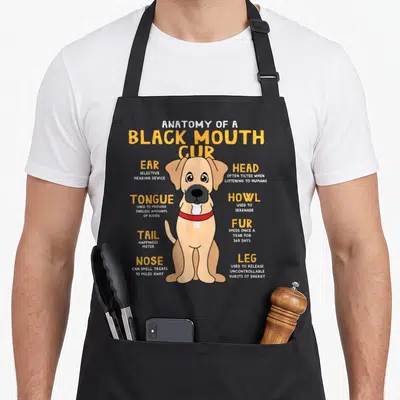 Mouth dog apron - Tan cartoon Black Mouth Cur with labeled anatomy parts and yellow text definitions — shown on a black cotton canvas apron against a white background