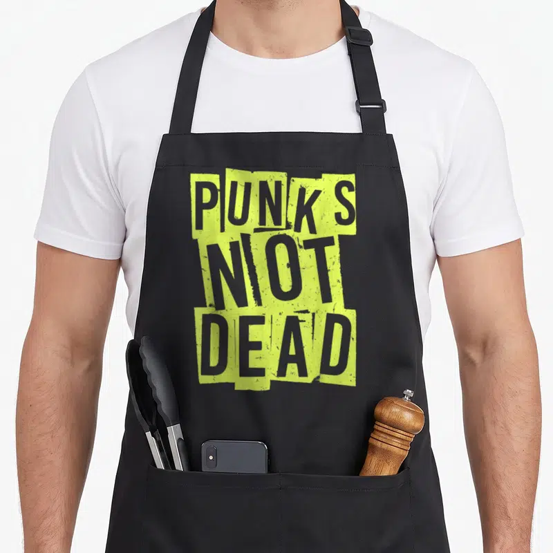 Guitar punk rock apron - PUNKS NOT DEAD text in distressed lime green blocks on grey background — shown on a black cotton canvas apron against a white background