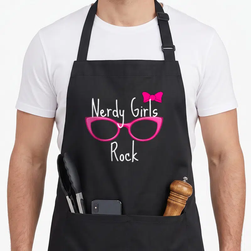 Nerdy geek aprons - Pink glasses with a bow and white Nerdy Girls Rock text — shown on a black cotton canvas apron against a white background