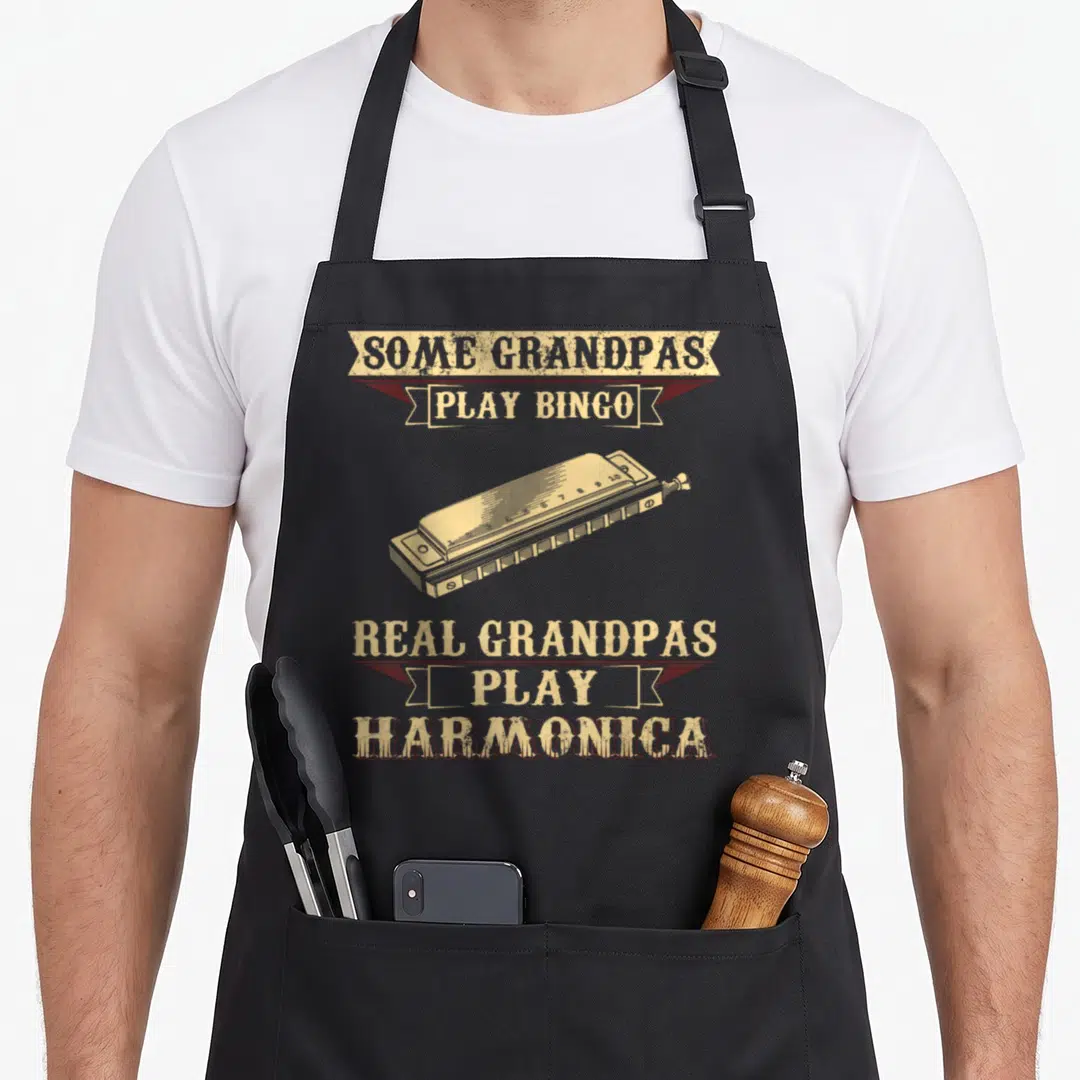 Harmonica bingo apron - Retro beige harmonica with maroon ribbons reading some grandpas play bingo real grandpas play — shown on a black cotton canvas apron against a white background