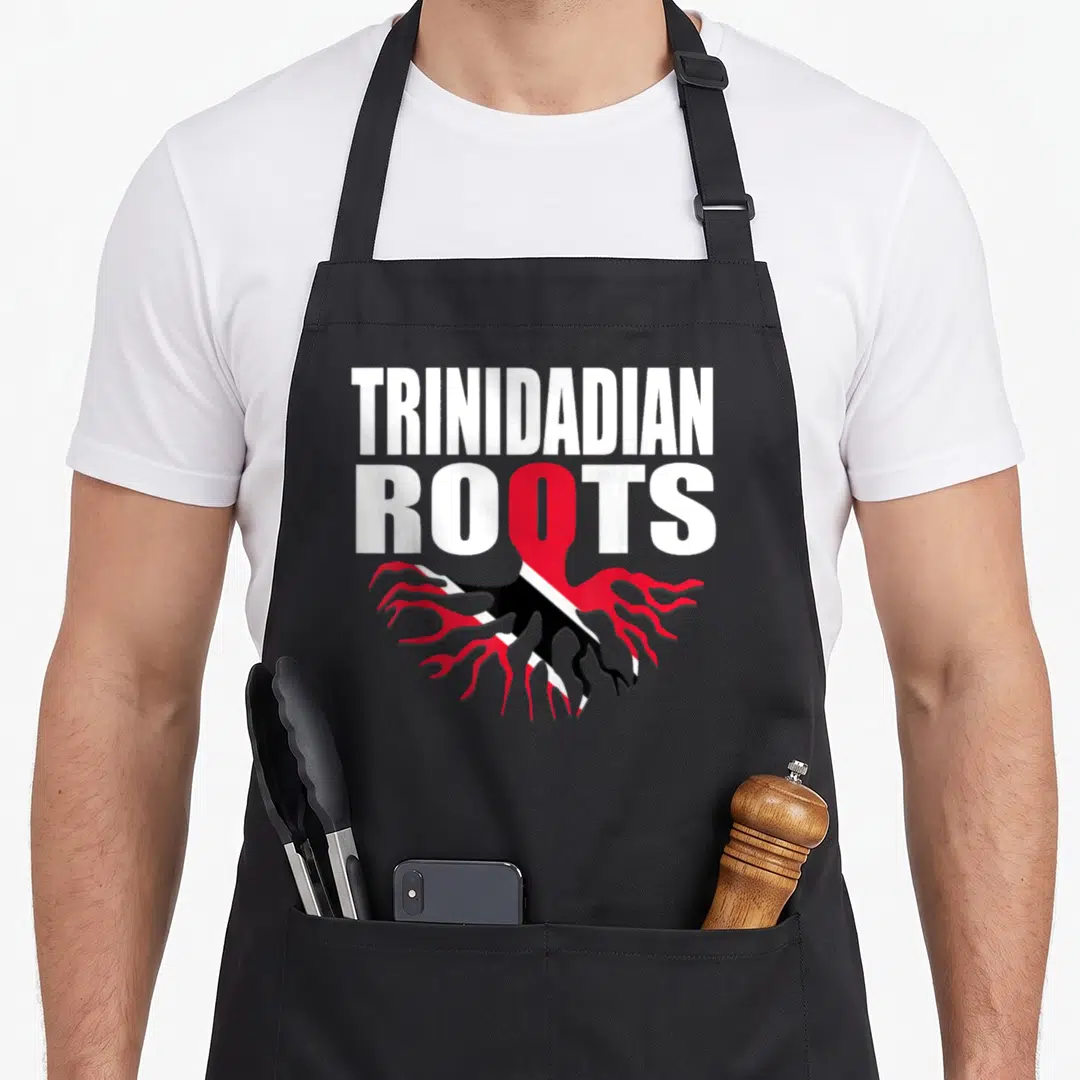 Root trinidadian boy apron - Stacked text TRINIDADIAN ROOTS with red O turning into flag-patterned roots in black — shown on a black cotton canvas apron against a white background