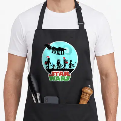 Holiday character aprons - Star Wars silhouettes with Santa hats carrying gifts labeled To WAN To DEATH under blue — shown on a black cotton canvas apron against a white background