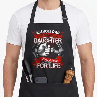 Smartass mom daughter aprons - Fist bump photo with Asshole Dad and Smartass Daughter text in white and red — shown on a black cotton canvas apron against a white background