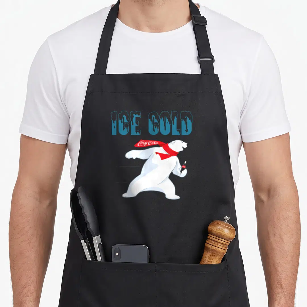 Cold bear apron - Blue ice gold text above white polar bear with red scarf holding bottle — shown on a black cotton canvas apron against a white background