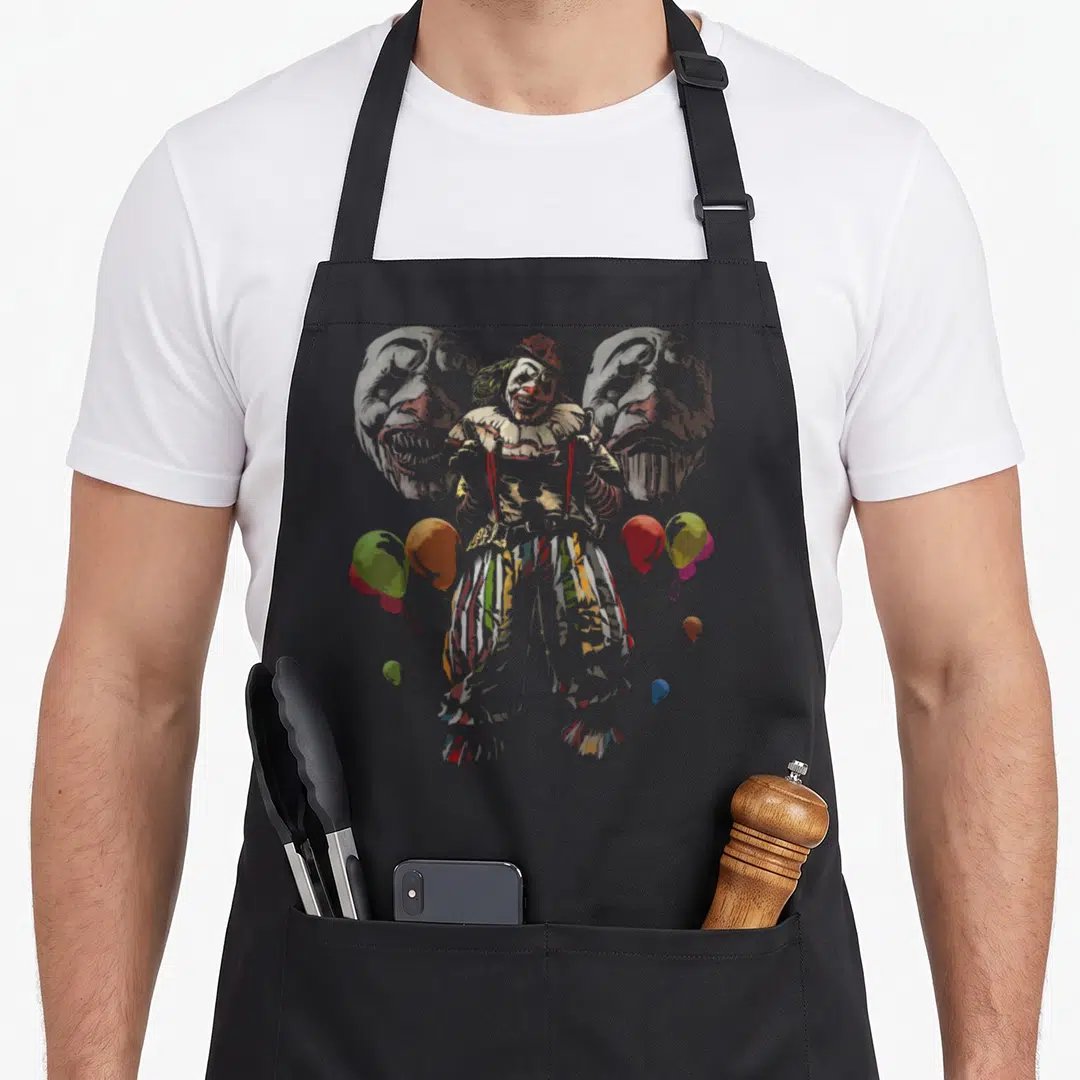 Creepy clown aprons - Central clown flanked by two ghostly faces with scattered red, yellow, green, and blue balloons — shown on a black cotton canvas apron against a white background